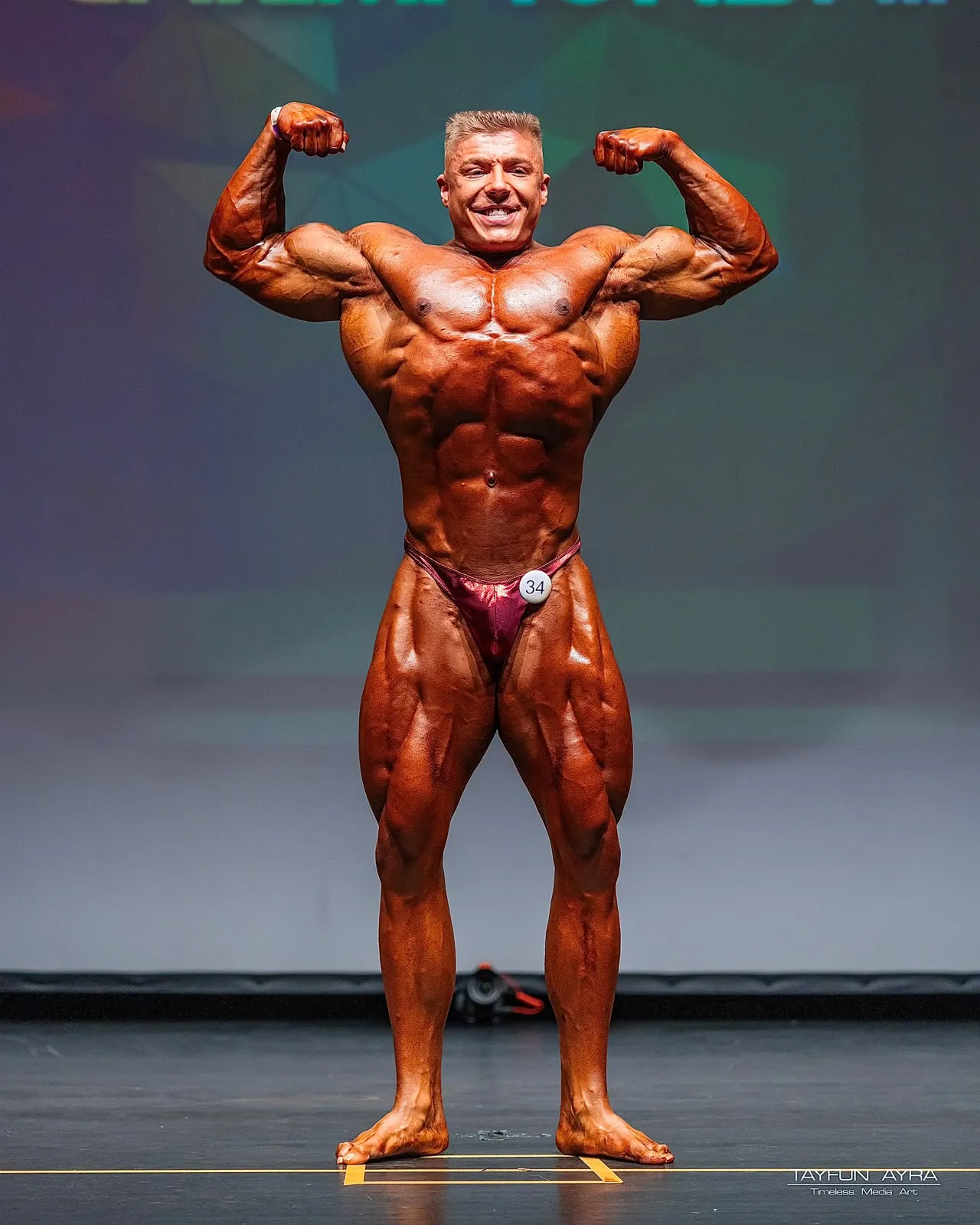 Young Rozy, Bodybuilder, beim Front Double Biceps auf der Wettkampfbühne